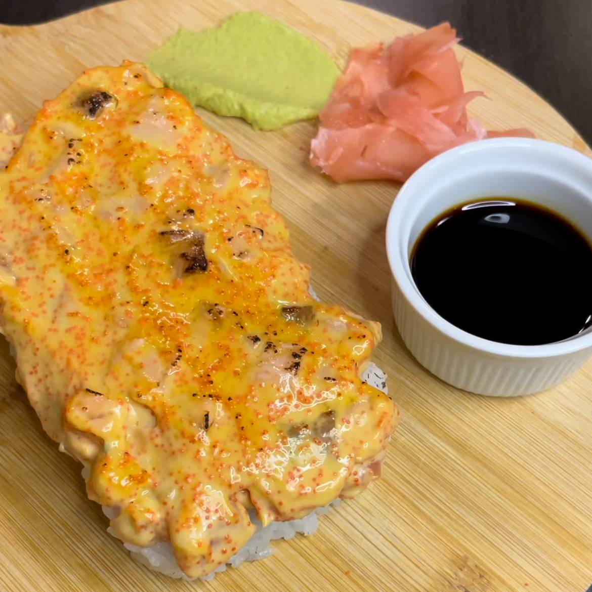 Pikants suši rullītis, pārklāts ar pikantu mērci, pasniegts ar wasabi, marinētu ingveru un sojas mērci